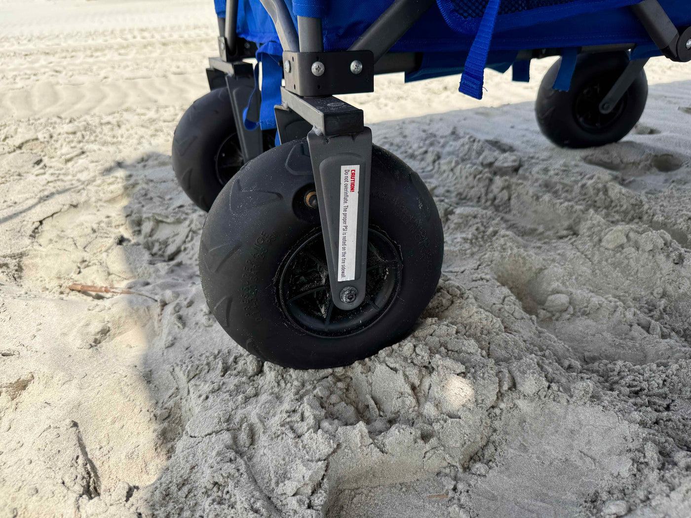 Close-up of a beach wheelchair's wheels on sandy terrain
